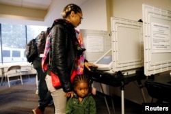 2-year-old Kadence Bethea waits for her mother Lindsey Adams to finish casting her vote in the midterm election after they waited in line for more than an hour and a half at a Fulton County polling place in Atlanta, Georgia, Nov. 6, 2018.