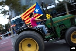 A woman drives a tractor decorated with a pro-independence flag during the Catalan National Day in Barcelona, Spain, Sept. 11, 2018.