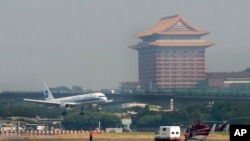 FILE - With the landmark Grand Hotel in rear, a plane carrying the first wave of mainland China tourists from the coastal city of Xiamen lands at the Taipei Airport, Friday, July 4, 2008, in Taipei, Taiwan.