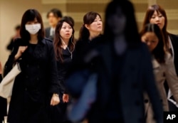 FILE - Female office workers head to their workplace during morning rush hour in Tokyo.