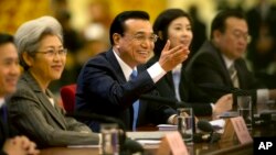 Chinese Premier Li Keqiang, center, smiles as he answers a reporter's question during a press conference at the end of the National People's Congress in Beijing's Great Hall of the People, March 15, 2015. 