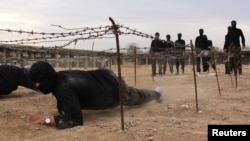 FILE - Islamist fighters crawl under razor wire at a training camp in near Damascus in this 2013 photo.