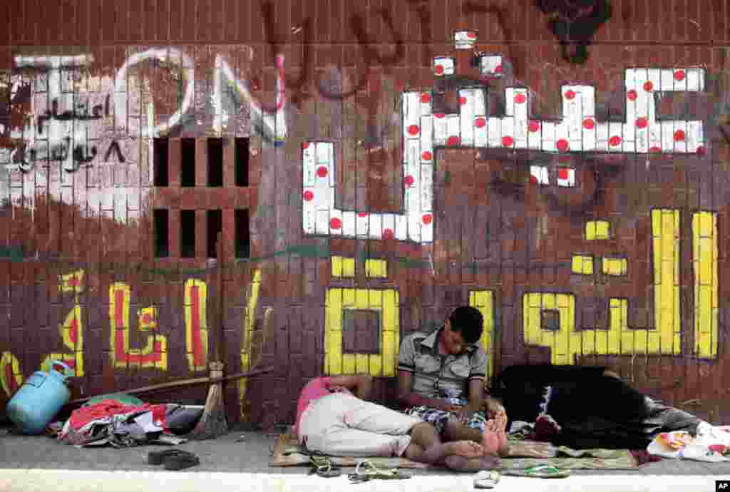 July 15: Protesters take a nap in the shade of a wall with painting that reads in Arabic " Live the revolution" during a demonstration in Tahrir Square in Cairo, Egypt. (AP Photo/Khalil Hamra)