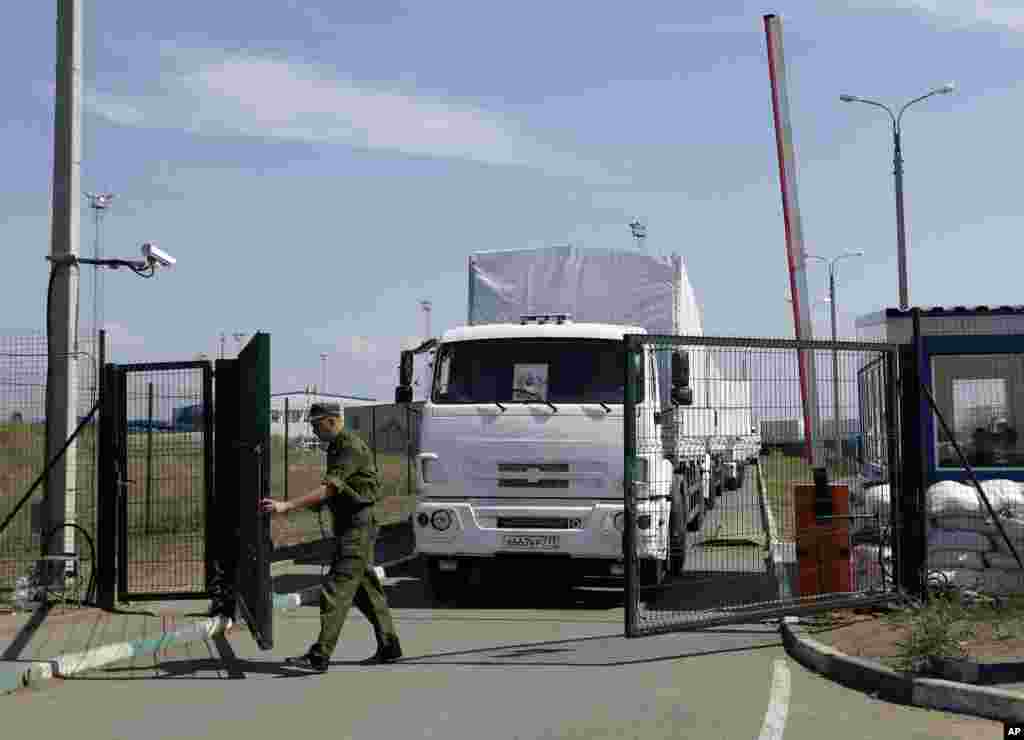 A Russian guard opens a border gate for passage into Ukraine for the first trucks heading into the country from the Russian town of Donetsk, Rostov-on-Don region, Russia, Aug. 22, 2014.