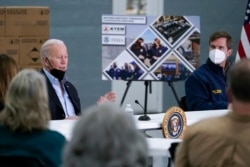 Kentucky Gov. Andy Beshear, right, listens as President Joe Biden speaks during a briefing from local leaders on the storm damage from tornadoes and extreme weather at Mayfield Graves County Airport in Mayfield, Ky., Dec. 15, 2021.