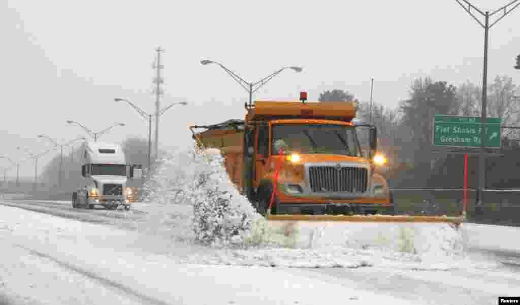 A snow plow knocks snow off the an Atlanta expressway during an ice storm in Atlanta, Georgia, Feb. 12, 2014. 