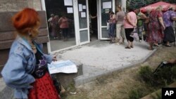 FILE - Local residents stand in line to get benefit payments outside the rebel headquarters in Donetsk, eastern Ukraine, Aug. 19, 2014. 