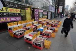 지난 4일 한국 서울 상가 앞을 신종 코로나바이러스 예방 마스크를 쓴 여성이 지나가고 있다.