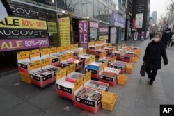 지난 4일 한국 서울 상가 앞을 신종 코로나바이러스 예방 마스크를 쓴 여성이 지나가고 있다.