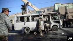 Afghan security force personnel inspect a damaged minibus at the site of a suicide attack in Kabul, Afghanistan, Dec. 11, 2014.