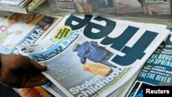 FILE - A customer holds a copy of the New Day at a newsstand in central London, Britain.
