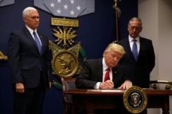 FILE - U.S. President Donald Trump signs an executive order he said would impose tighter vetting to prevent foreign terrorists from entering the United States, at the Pentagon, in Arlington, Virginia, Jan. 27, 2017.