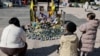 People gather around a makeshift memorial in front of portraits of late Israeli hostages Shiri, Ariel, and Kfir Bibas, as well as Oded Lifshitz at Hostages Square in Tel Aviv on Feb. 25, 2025, a day ahead of the Bibas family funeral.