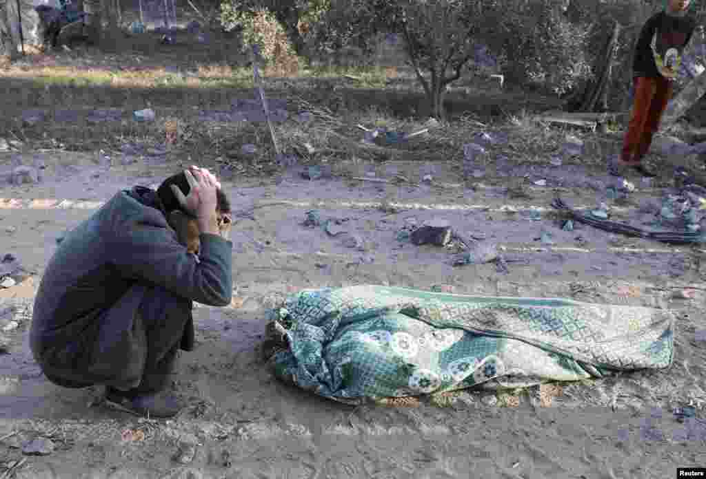 A person reacts next to a body, in the aftermath of an Israeli strike on a house, in Deir Al-Balah, in the central Gaza Strip.