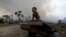 FILE - Jose, 2, plays while a fire burns a tract of Amazon jungle as it is cleared by loggers and farmers near Porto Velho, Brazil, Aug. 27, 2019. 