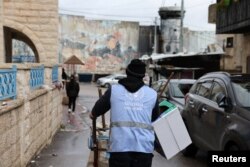 Seorang pekerja UNRWA mendorong gerobak di kamp pengungsi Aida di Betlehem di Tepi Barat yang diduduki Israel, 5 Februari 2024. (Foto: REUTERS/Mussa Qawasma)