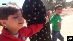 FILE - This frame grab from video provided by Muaz al-Shami, Syrian Revolution Network, an opposition activist media organization, that is consistent with independent AP reporting, shows children pulled by an adult after airstrikes killed nearly 30 people, mostly children, in the northern rebel-held village of Hass, Syria, Oct. 26, 2016.