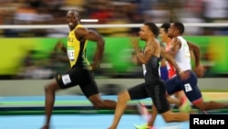 Le Jamaïcain Usain Bolt regarde le Canadien André De Grasse lors des demi-finales 100 mètres homme, à Rio de Janeiro, Brésil, le 14 août 2016.