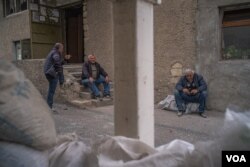 Men sit outside an underground shelter before bombs and sirens go off in Nagorno-Karabakh, Oct. 9, 2020. (Yan Boechat/VOA)