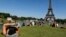 FILE - A woman reads a book as she rests in a public garden near the Eiffel Tower on a hot summer day in Paris, July 3, 2014. 