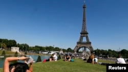 FILE - A woman reads a book as she rests in a public garden near the Eiffel Tower on a hot summer day in Paris, July 3, 2014. REUTERS/Gonzalo Fuentes (FRANCE - Tags: TRAVEL ENVIRONMENT SOCIETY) - RTR3X04W