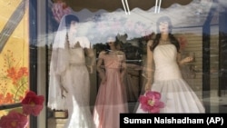 FILE - Mannequins in wedding gowns are seen in a window display on March 15, 2021, at a bridal store in Nogales, Ariz., that has been closed for nearly a year because of the pandemic.AP Photo/Suman Naishadham, File)