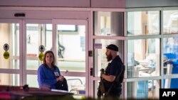 Um agente da autoridade armado guarda a entrada da ambulância no Central Maine Medical Center em Lewiston, Maine, na madrugada de 26 de outubro de 2023.