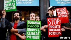 FILE: Environmental activists hold signs reading "Stop fossil energy project", "Uganda, rights and climate trampled" and "Total withdrawal from Russia" during a protest disrupting shareholder meeting of TotalEnergies, in Paris on May 25, 2022.