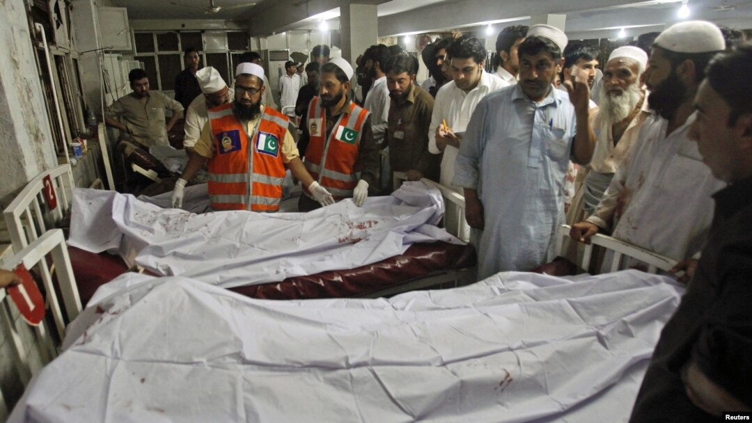 Polisi dan petugas rumah sakit berdiri dekat jenazah korban bom mobil di Peshawar, Pakistan. (Foto: Reuters)