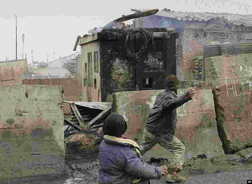 Afghans throw stones towards U.S. soldiers in front of the US base of Bagram during an anti US demonstration in Bagram, Afghanistan, February 21, 2012. (AP)