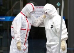 FILE - Medical workers wearing protective gears comfort each other outside a hospital in Daegu, South Korea, Feb. 28, 2020.