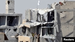 Fighters of Syrian Democratic Forces raise a white flag near the National Hospital complex where the Islamic State militants are holed up, at the frontline in Raqqa, Syria, Oct. 16, 2017. 