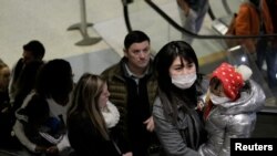 Travelers wearing masks arrive on a direct flight from China on Jan. 23, 2020, at Seattle-Tacoma International Airport.
