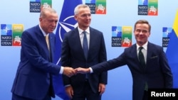 El Pdte. de Turquía, Recep Tayyip Erdogan, a la izquierda, le da la mano al primer ministro de Suecia, Ulf Kristersson, a la derecha, mientras el secretario general de la OTAN, Jens Stoltenberg, observa previo a la cumbre de la OTAN en Vilna, Lituania, el 10 de julio de 2023. 