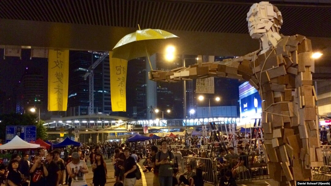 香港民間藝術家製作的巨型撐傘人體塑像在政府總部外的抗議場地擺放。