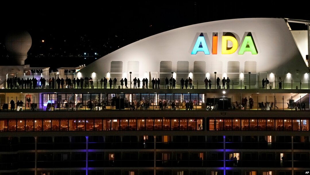 Orang-orang berdiri di atas dek kapal pesiar asal Jerman AIDAnova yang berlabuh di Lisbon, tepat sebelum tengah malam Tahun Baru pada 31 Desember 2021. (AP/Armando Franca)