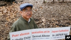 Katsumi Takenaka holds a protesting banner during an interview with The Associated Press in Tokyo, Dec. 10, 2019.