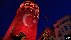ພວກຄົນຈຳນວນໜຶ່ງ ກຳລັງຖ່າຍຮູບ ຢູ່ທີ່ Galata Tower ທີ່ເປັນສັນຍາລັກ ຂອງປະເທດເທີກີ, ຊຶ່ງໄດ້ຖືກແຍງແສງ
ໄຟເປັນຮູບພາບຂອງທຸງຊາດ ໃສ່ນັ້ນ ຢູ່ໃນນະຄອນ Istanbul, ວັນທີ 30 ກໍລະກົດ 2016. 