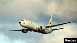 FILE - A P-8A Poseidon surveillance plane conducts flyovers above the Enterprise Carrier Strike Group in this handout photo courtesy of the U.S. Navy, Feb. 3, 2012.