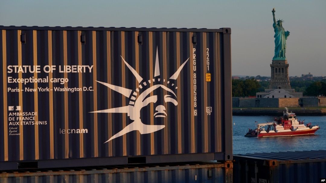 Sebuah peti kemas yang membawa replika Patung Liberty, kiri, melintas di depan Patung Liberty berukuran penuh saat tiba dari Perancis dengan kapal kontainer di New York, Rabu, 30 Juni 2021. (Foto: AP)