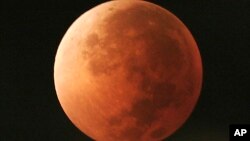 FILE - In this Aug. 28, 2007 photo, the moon takes on different orange tones during a lunar eclipse seen from Mexico City. On Jan. 31, 2018, a supermoon, blue moon and a lunar eclipse will coincide for first time since 1982 and will not occur agai