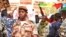 A national guard soldier walks by demonstrators at Bamako airport, Mali. (VOA - N. Palus)