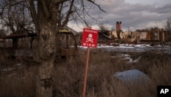 FILE - A sign that reads "Mines" is placed on the side of the road in the village of Kamyanka, Ukraine, on Feb. 19, 2023. In this war-scarred city in Ukraine's northeast, residents scrutinize every step for land mines. 