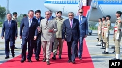 This handout photograph taken and released by Pakistan's Prime Minister Office on October 14, 2024 shows China's Premier Li Qiang, center left, speaking with Pakistan's Prime Minister Shehbaz Sharif upon his arrival at the Chaklala military air base inIslamabad.