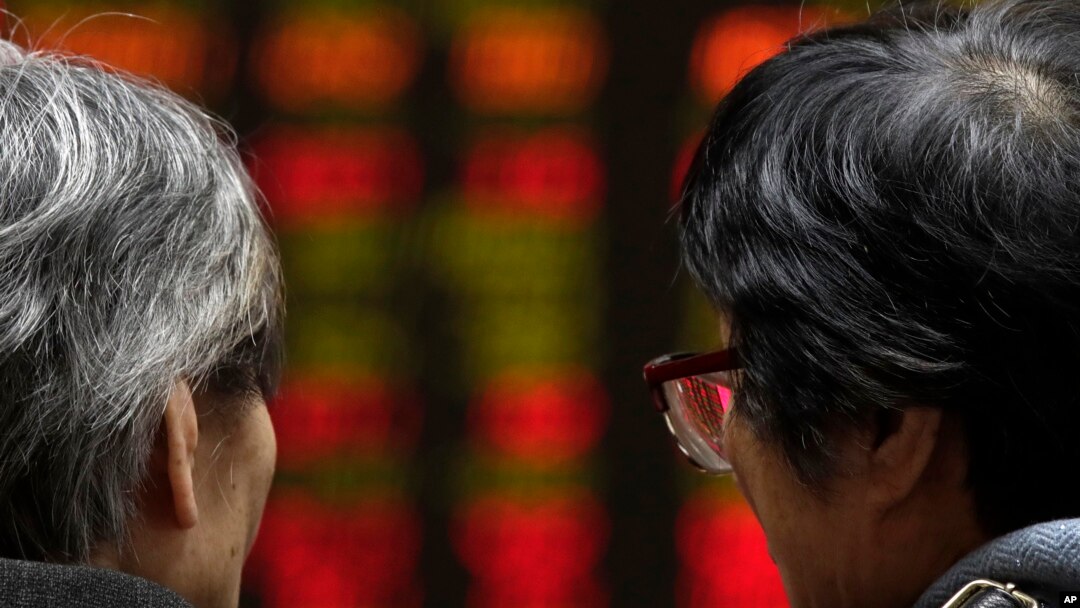 Dua pialang saham perempuan berbicara sambil mengamati pergerakan saham di Bursa Saham Beijing, China, Senin (26/3).