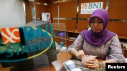 FILE - An employee of Bank Negara Indonesia (BNI) counts rupiah banknotes at the BNI headquarters in Jakarta.