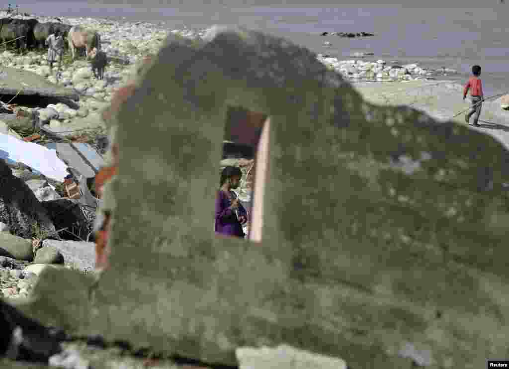 A girl walks amidst the debris of a flood-damaged house on the banks of the river Tawi in Jammu, Sept. 8, 2014.