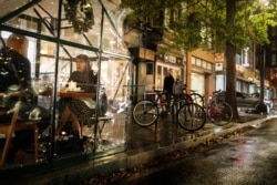 FILE - Restaurant patrons sit inside plastic tents while being served outside of the Lupo Verde restaurant along the 14th Street Corridor amid the coronavirus outbreak, in Washington, Dec. 4, 2020.