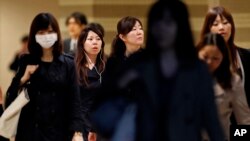 FILE - Female office workers head to their workplace during morning rush hour in Tokyo.