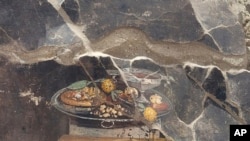 ARCHIVO - Esta imagen proporcionada el martes 27 de junio de 2023 por el Sitio Arqueológico de Pompeya muestra la pared de una antigua casa pompeyana con un fresco que representa una mesa con comida. 